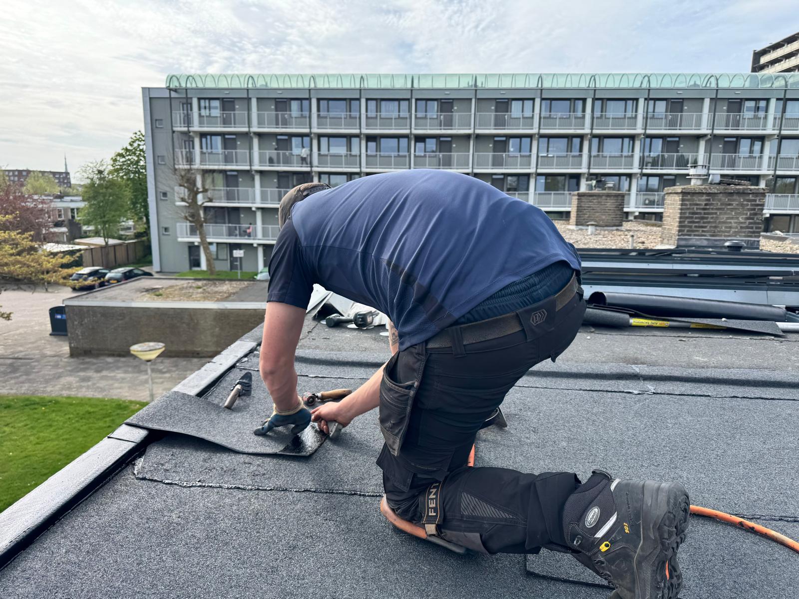 Monteur van Groningen Isoleert aan het werk op een plat dak in Groningen